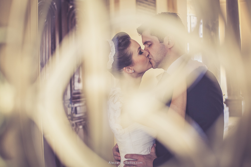 belo desfoque das grades do prédio nas fotos do casamento em bh no buffet catharina dos noivos na fotografia em belo horizonte para o fotografo bh no museu de artes e ofícios e o casal dando um beijo