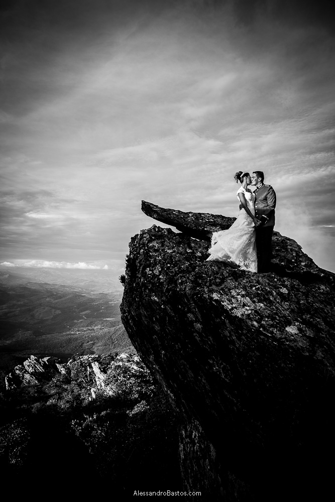 rocha acolhe os noivos nas fotografias após o casamento em bh na serra da piedade com as nuvens em preto e branco cortando o céu