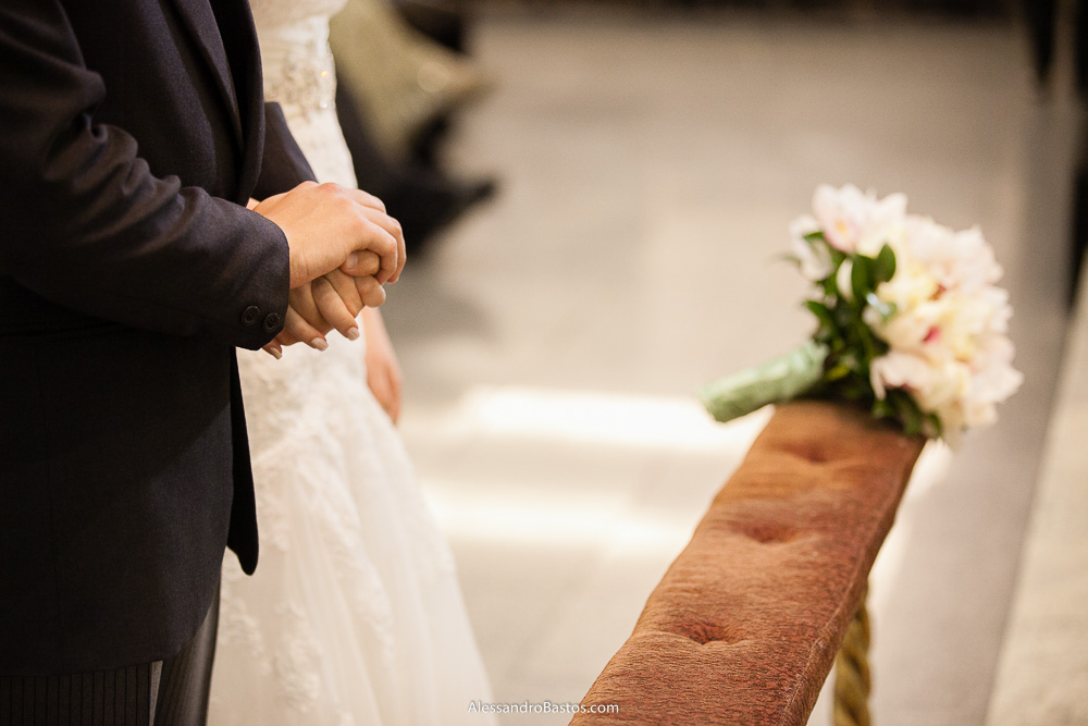 encontro de mãos dos noivos nas fotos do casamento em bh na igreja nossa senhora rainha em belo horizonte e a festa para fotografia dos noivos no jardim canada eventos para o fotografo e no fundo aparece o seu buquê branco