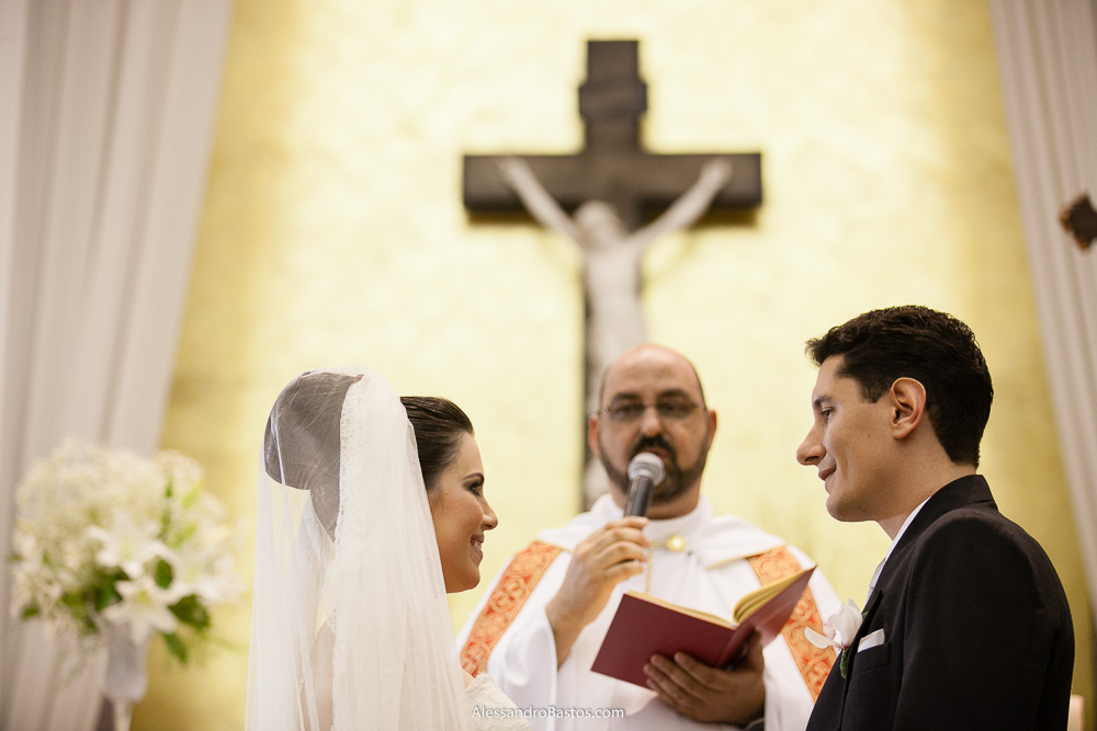 padre aparece ao fundo nas fotos do casamento em bh na igreja nossa senhora rainha em belo horizonte e a festa para fotografia dos noivos no jardim canada eventos para o fotografo bem na hora da benção