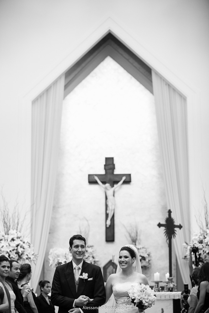 saída dos noivos nas fotos do casamento em bh na igreja nossa senhora rainha em belo horizonte e a festa para fotografia dos noivos no jardim canada eventos para o fotografo e no fundo a cruz