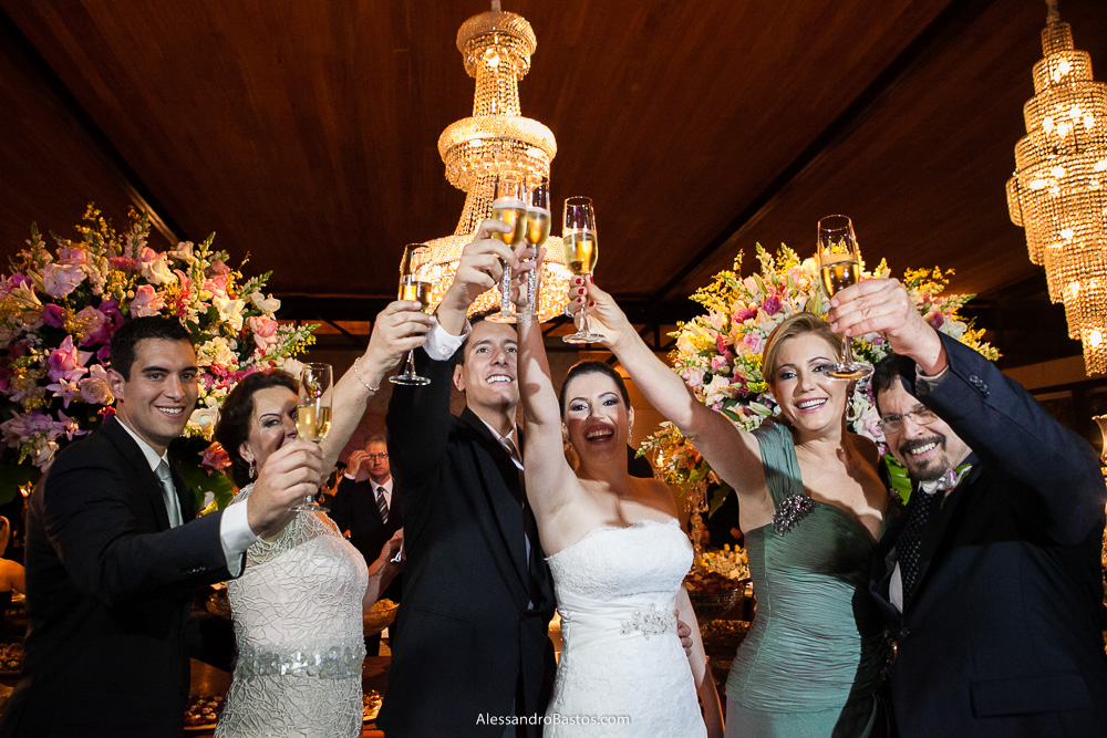 pais brindam com os noivos nas fotos do casamento em bh no jardim canada eventos em belo horizonte e a festa para fotografia dos noivos no jardim canada eventos para o fotografo e em frente a mesa do bolo e doces
