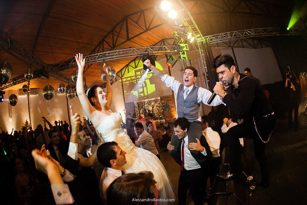 carregados pelos convidados os noivos dançam nas fotos do casamento em bh no jardim canada eventos em belo horizonte e a festa para fotografia dos noivos no jardim canada eventos para o fotografo e ao lado direto está o cantor