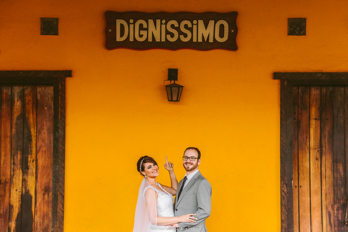 dignissimo está escrito em uma placa da vendinha fotografo casamento bh fotos noivos poswed fotografia pos-wedding belo horizonte macacos e a noiva aponta para o nome do local