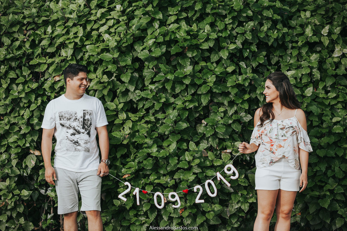 plaquinha com a data do casamento em bh os noivos seguram durante sessão de fotos pré-wedding no solar do engenho mostrando que eles vão se casar em setembro