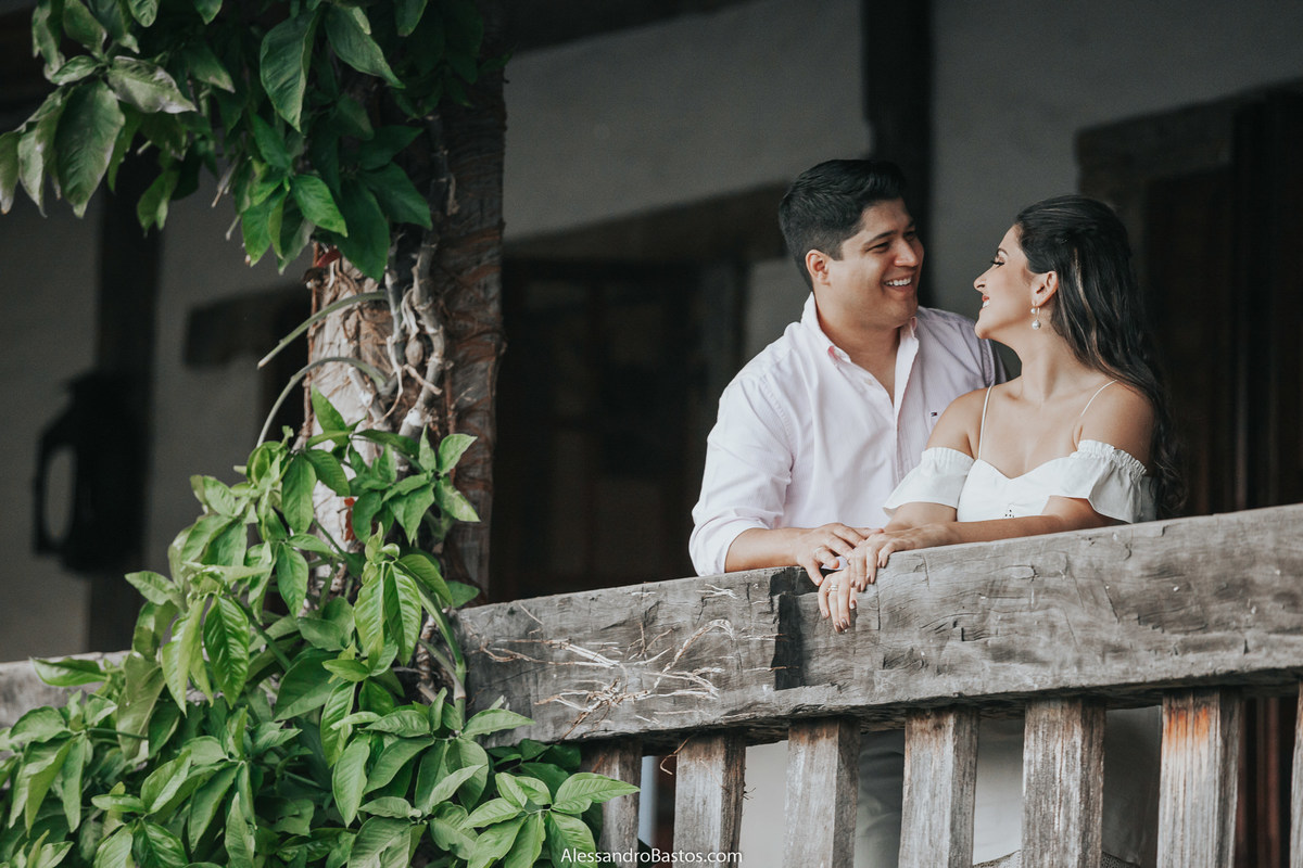 olho no olho e sorrindo os noivos ficam na varanda do solar do engenho com uma vegetação linda ao lado deles no pré-wedding para casamento em bh e sete lagoas cidade