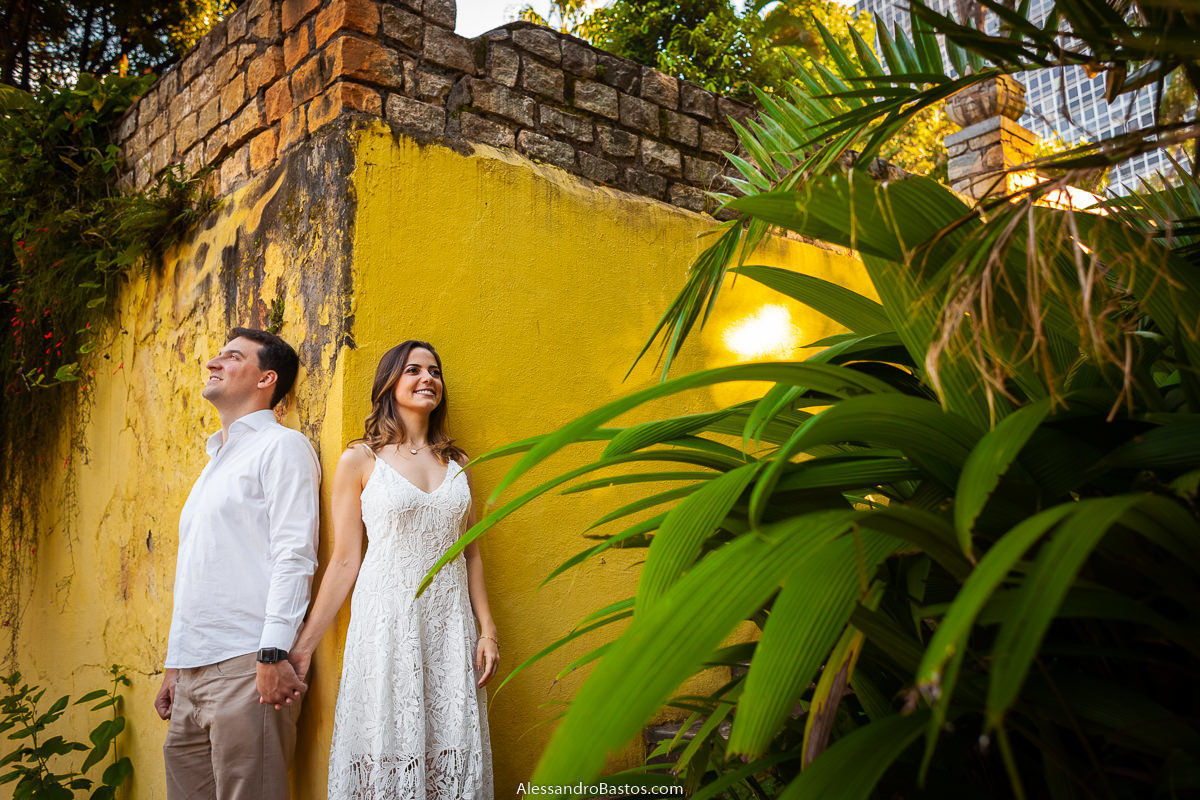 parede amarela de fundo nas fotos de noivos para casamento em bh fotografo com a vegetação na frente