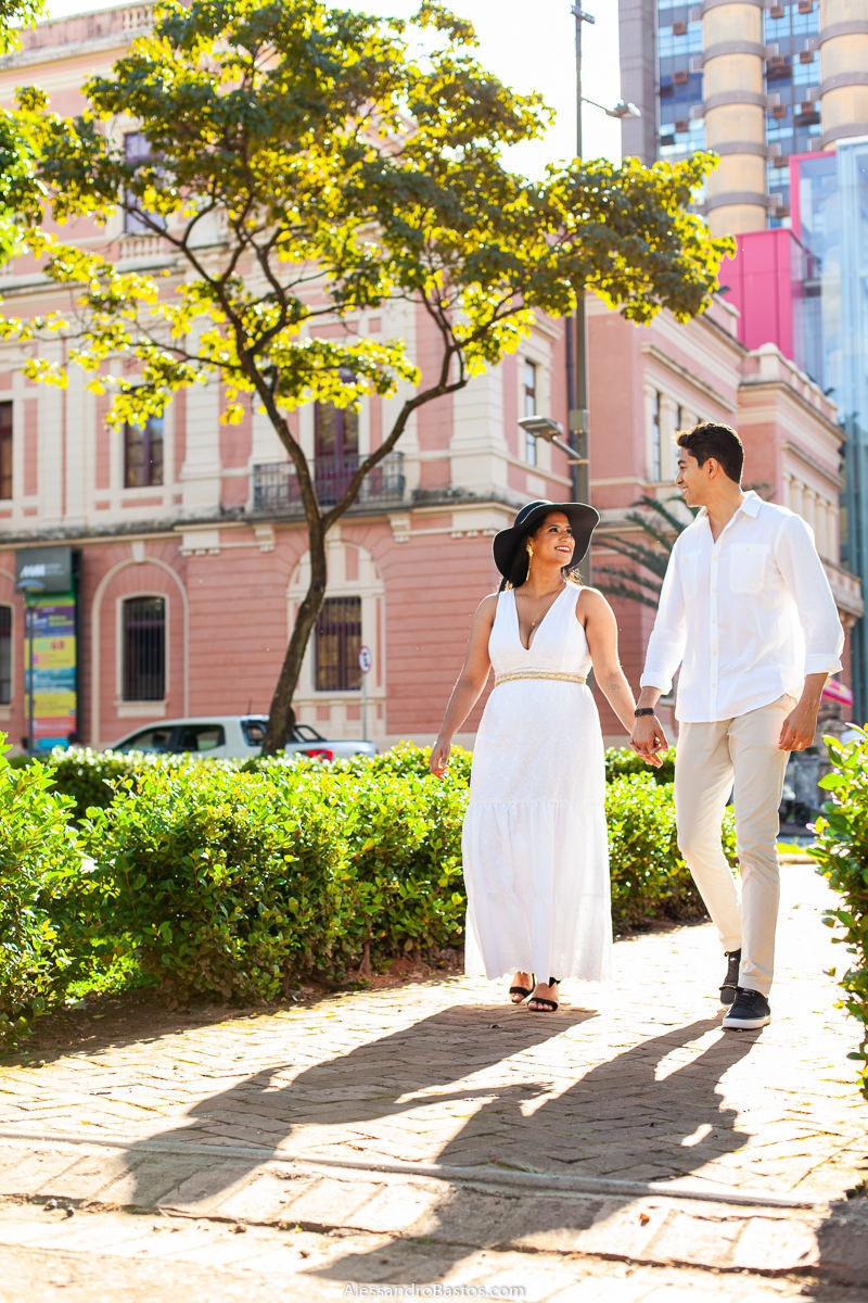 de mãos dadas nas fotos para o fotografo de noivos para casamento em belo horizonte caminham pela praça