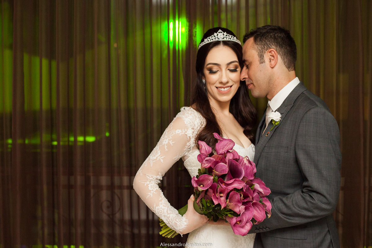 olhando para o buquê nas fotos fotografo do casamento dos noivos em bh belo horizonte no espaço maggiore enquanto o noivo dá um cheirinho na noiva