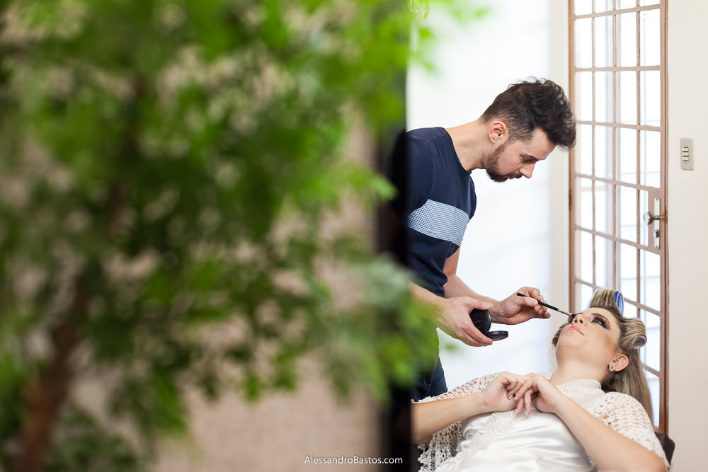 Lazaro Lambertucci maquiando a noiva camila no seu salão em BH com uma árvores desfocando o primeiro plano