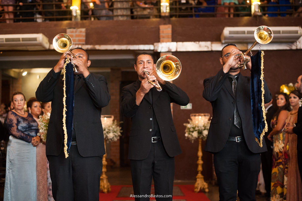 de repente três rapazer com cornetas entram na cerimônia do casamento no caravaggio em bh anunciando a entrada da noiva Camila de forma magnífica