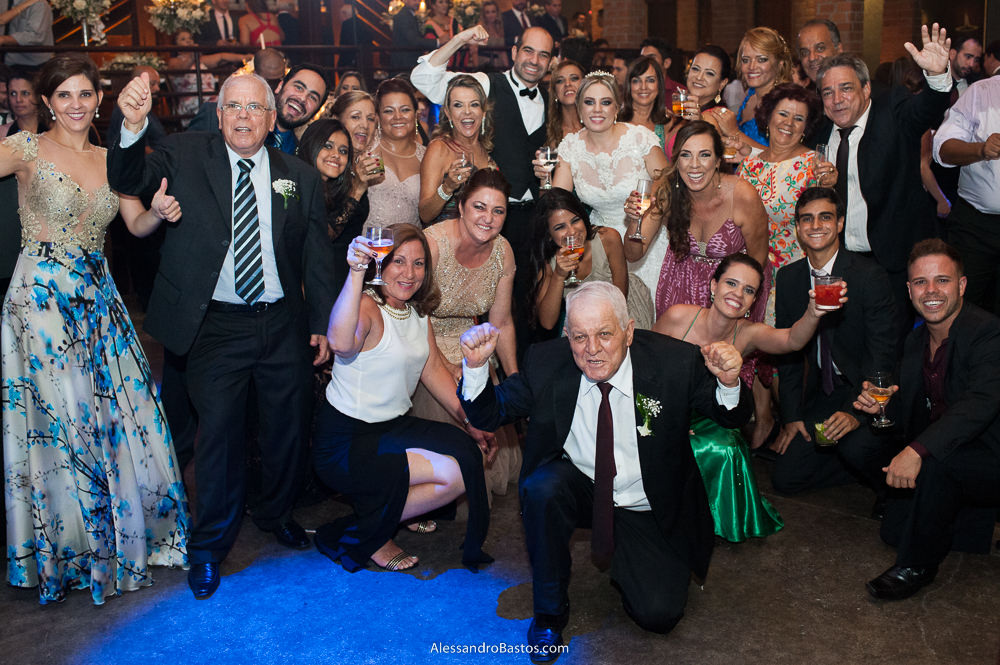 enorme grupo de amigos no casamento bh no caravaggio uma foto bem panorâmica do momento da festa do casamento bh no caravaggio com muitas cores vivas com os noivos bem no meio