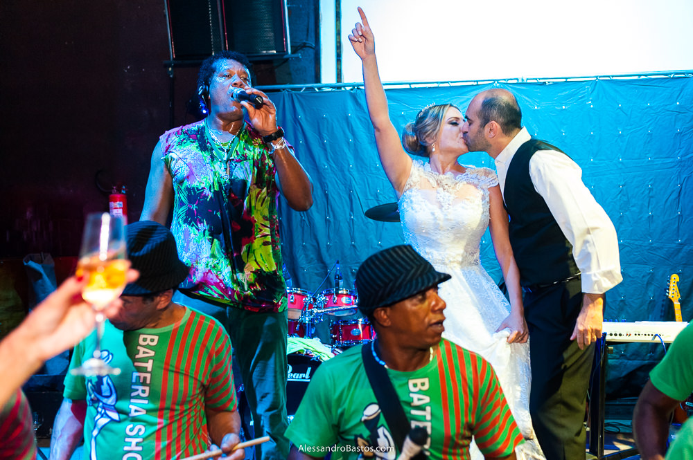 no palco da banda de samba do casamento no caravaggio em bh o mestre linguinha agita os convidados e os noivos dão um beijo com ela levantando um dos braços