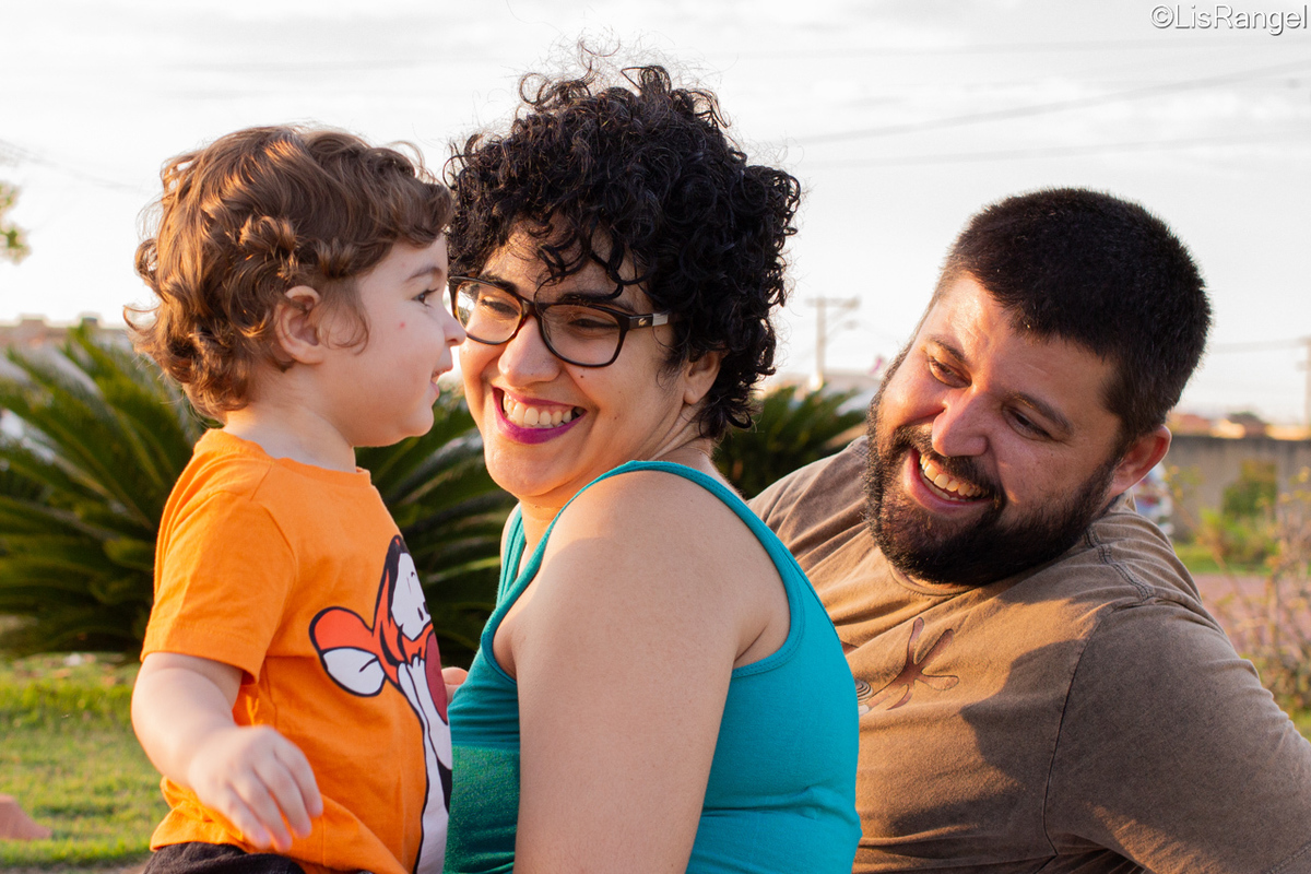 Mãe e pai lado a lado olhando o filho que está do lado deles.