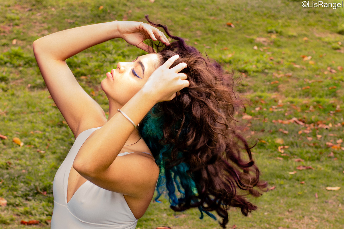 Mulher de olhos fechados, jogando cabelo pra cima.