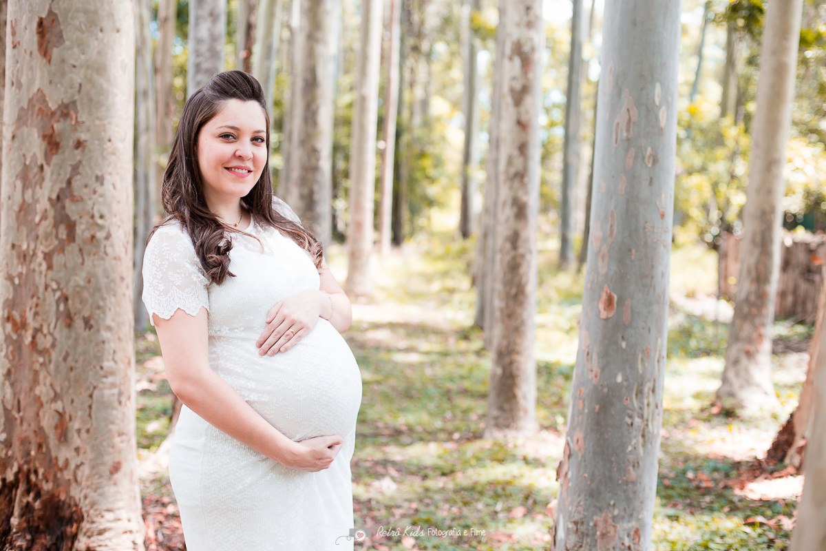 ensaio gestante com árvores grandes ao fundo do parque