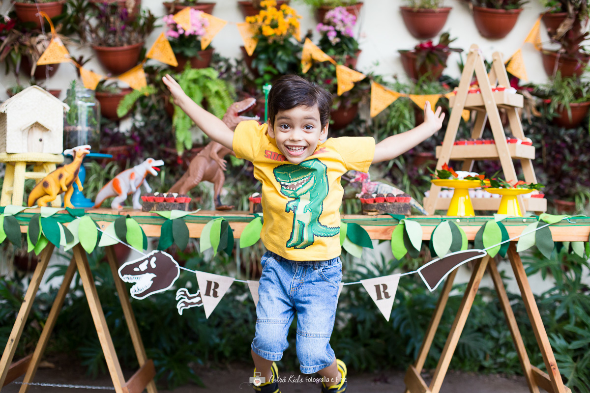 Fotografia da festa do gui pulando em frente a mesa do bolo