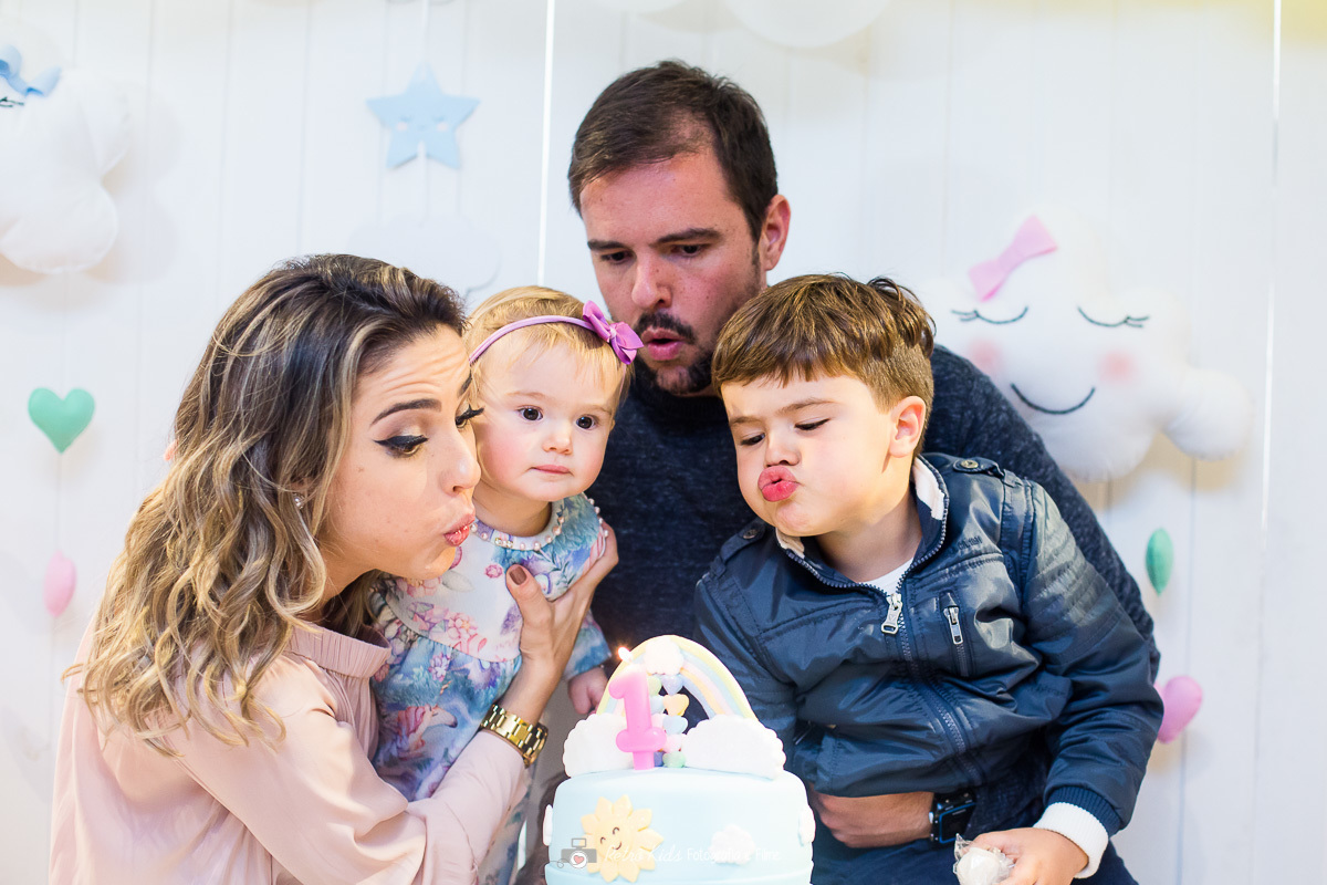 família assoprando as velinhas durante a música do parabéns na festa de aniversário da Júlia de 1 aninho