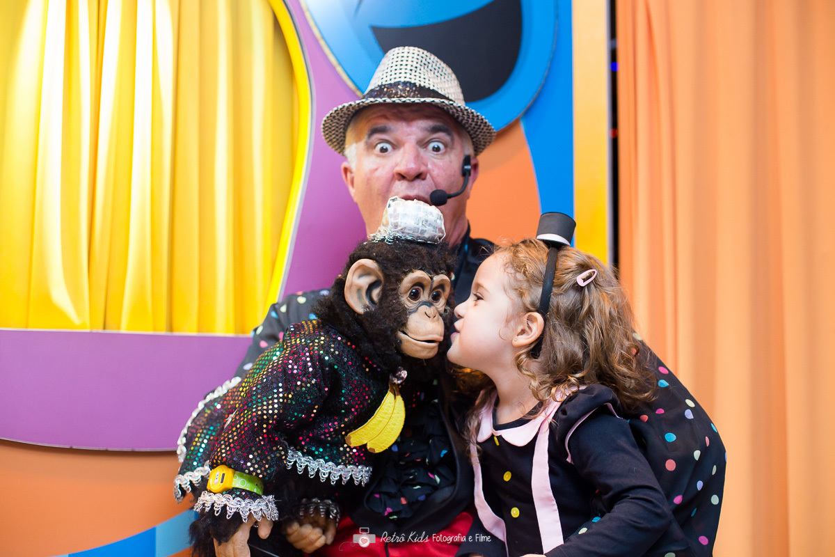 Criança beijando o macaco durante show de mágica com o palhaço na festa com tema O Mundo de Bita