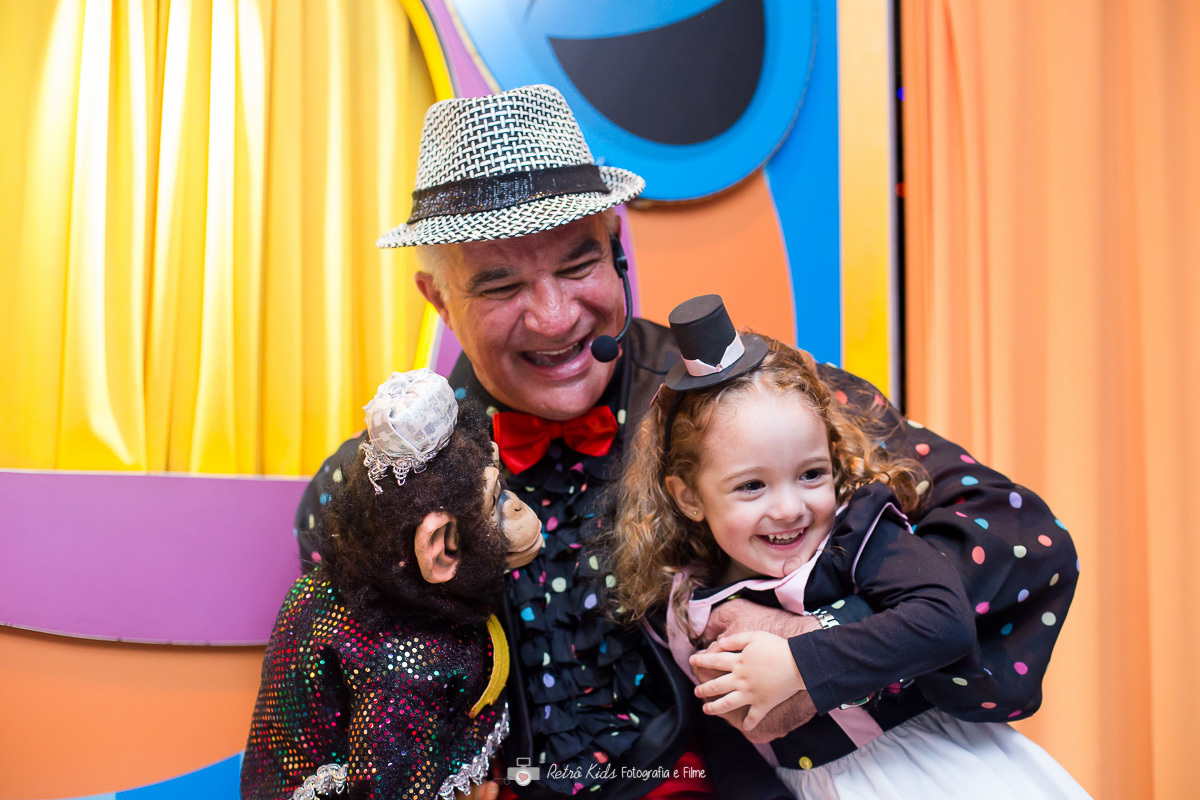 Criança sorrindo com o mágico e macaco durante o show de mágica