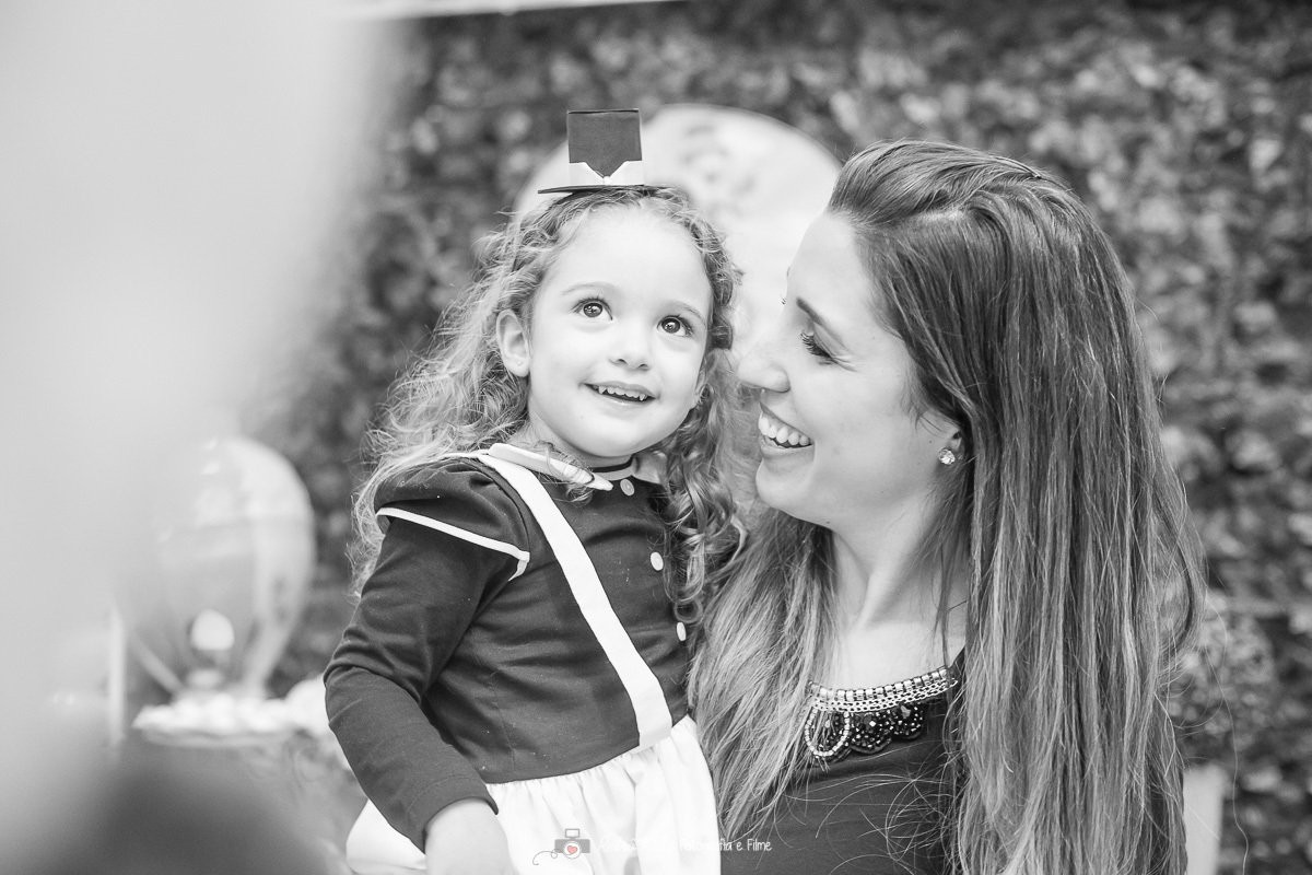Fotografia preta e branco de mãe e filha em frente a mesa decorada