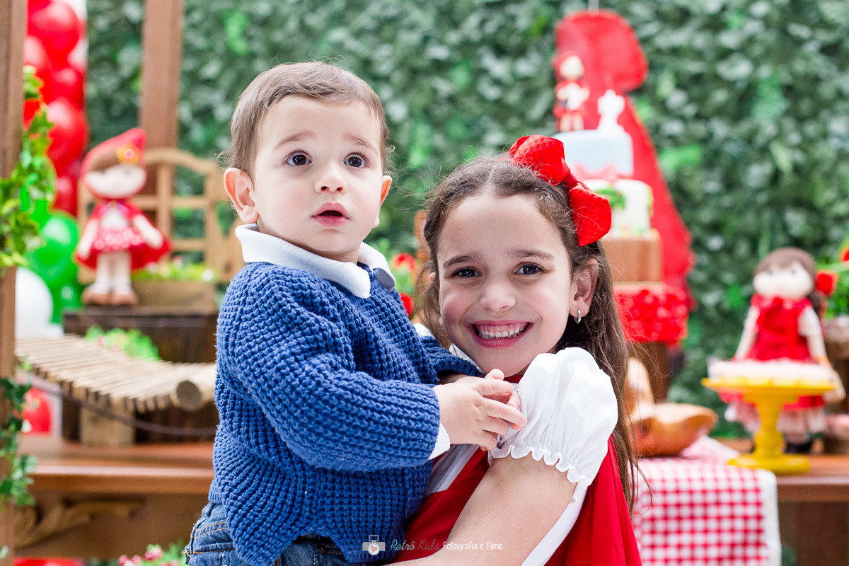 Maria Carolina com o irmã mais novo em frente a decoração da mesa no Buffet Spasso Magic em SP