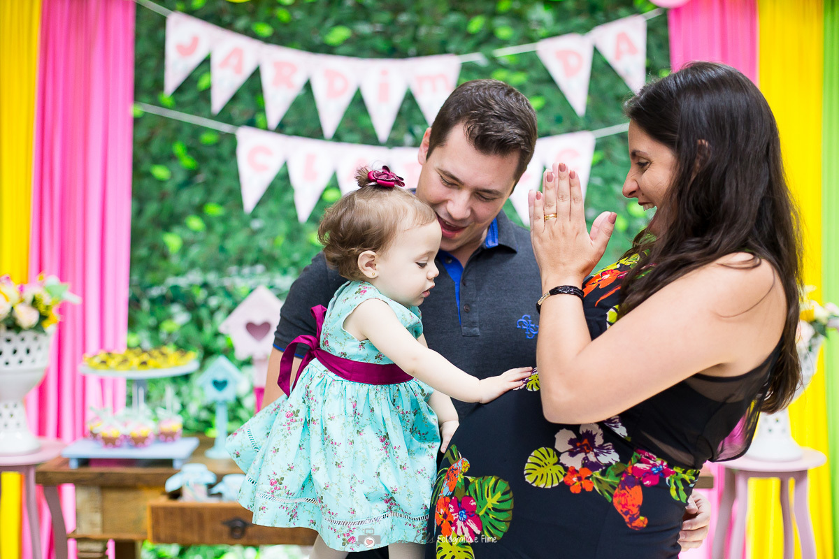 Retrato com a madrinha grávida em frente a mesa do aniversário infantil com o tema Jardim Encantado
