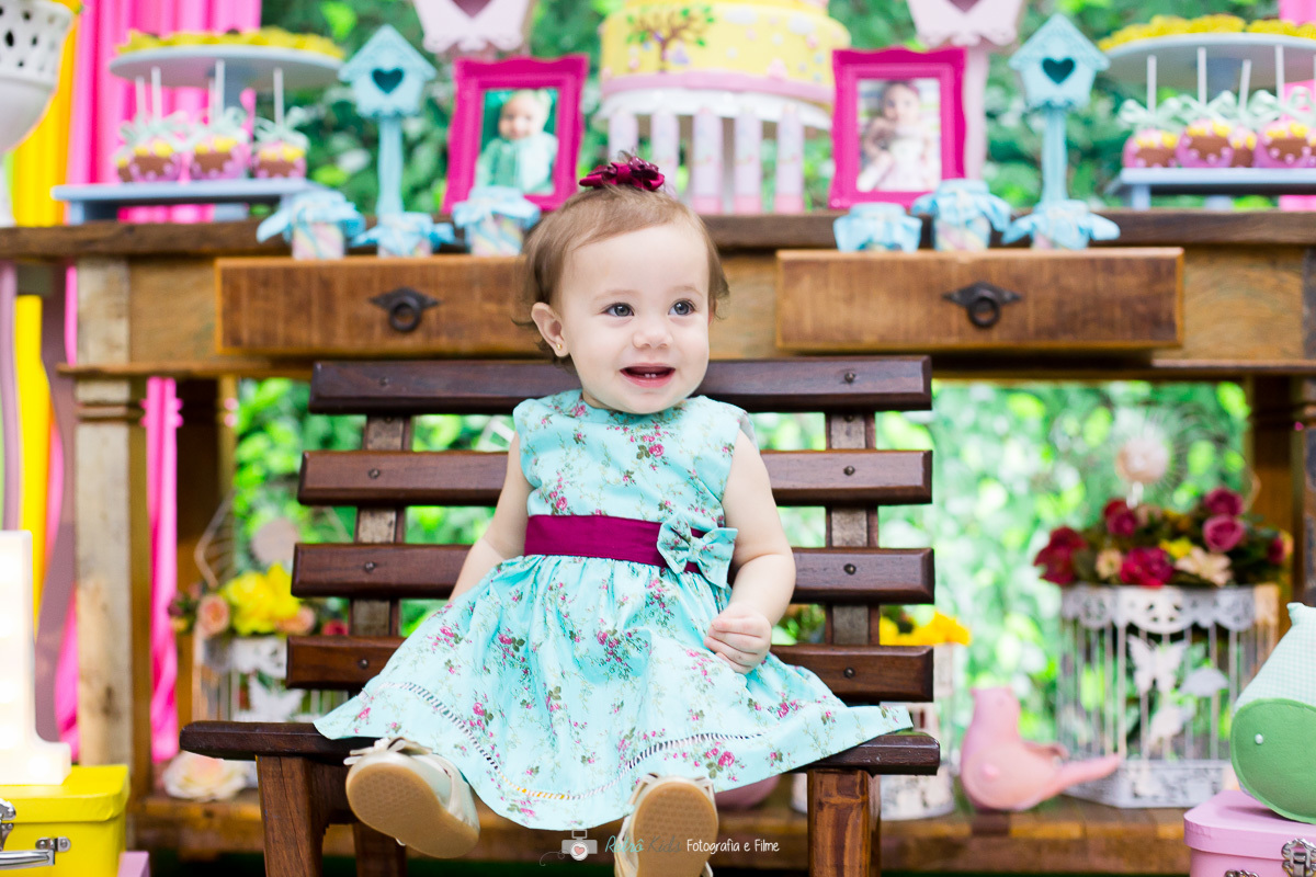 Clarice sentada no banco de madeira do Jardim Encantado na sua festa de 1 aninho no Buffet Kairós Ipiranga SP