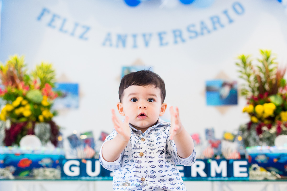 Guilherme brincando na sua festa de 1 aninho na sua mesa decorada com o tema o fundo do mar