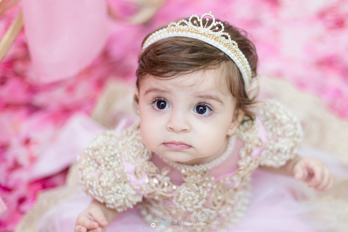 Retrato da Luiza em frente sua mesa decorada com o tema realeza