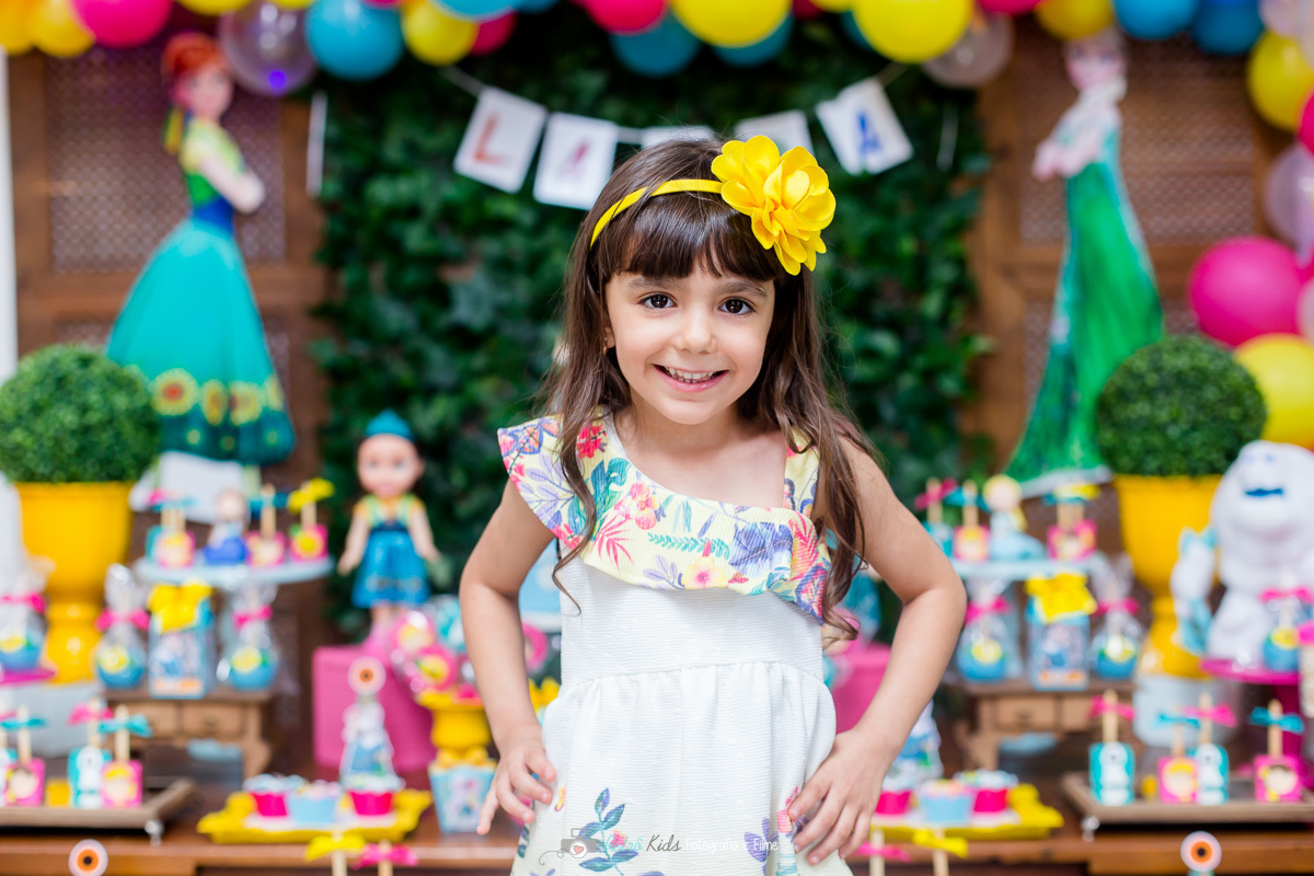 Laura muito feliz para o retrato em frente a sua mesa decorada da Frozen Fever no Buffet Espaço Jack Kingdom.