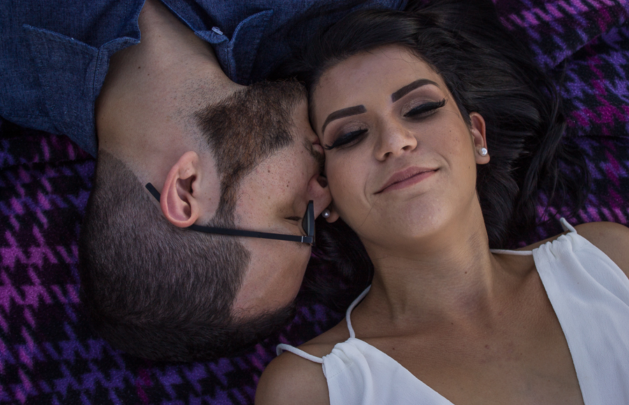 ENSAIO FOTOGRAFICO DE CASAL PRE WEDDING DEITADOS NA TOALHA  DE PIQUENIQUE ROXA AO AR LIVRE BEIJO MARINGA PARANA
