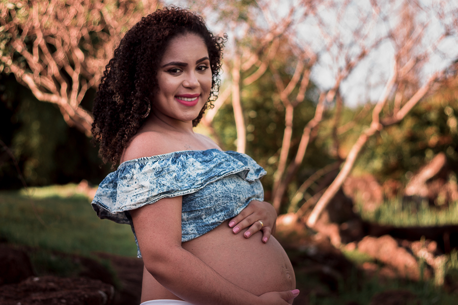 ENSAIO FOTOGRAFICO DE GESTANTES NO PARQUE DO JAPAO EM UMA TARDE ENSOLARADA EM MARINGA PARANA BRASIL NA IMAGEM A GESTANTE ESTA SEGURANDO A BARRIGA E OLHANDO EM DIRECAO A FOTO COM FUNDO UMA ARVORE SEM FOLHAS DESFOCADA
