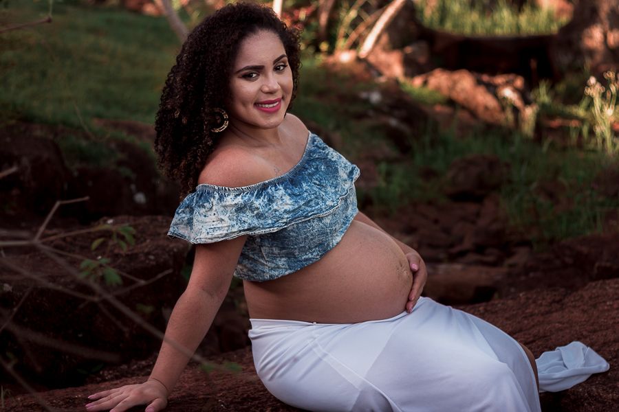 ENSAIO FOTOGRAFICO DE GESTANTES NO PARQUE DO JAPAO EM UMA TARDE ENSOLARADA EM MARINGA PARANA BRASIL NA IMAGEM A GESTANTE ESTA SENTADA EM UMA PEDRA COM UMA DAS MAOS NA BARRIGA E OLHANDO PARA A FOTO