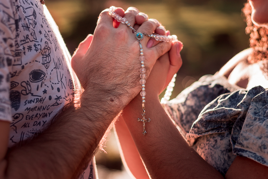 ENSAIO FOTOGRAFICO DE GESTANTES NO PARQUE DO JAPAO EM UMA TARDE ENSOLARADA EM MARINGA PARANA BRASIL NA IMAGEM DE DETALHE ESTA O CASAL COM AS MAOS DADAS E COM UM TERCO ENVOLTO SIMBOLIZANDO A SUA FE