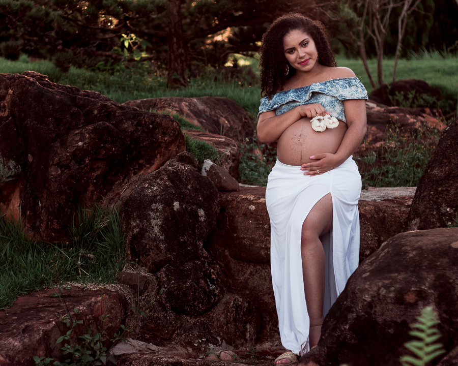 ENSAIO FOTOGRAFICO DE GESTANTES NO PARQUE DO JAPAO EM UMA TARDE ENSOLARADA EM MARINGA PARANA BRASIL NA IMAGEM A MAMAE SEGURA UM SAPATINHO DA FILHA EM CIMA DA BARRIGA EM MEIO A PEDRAS ORNAMENTAIS ESTILO JAPONESAS