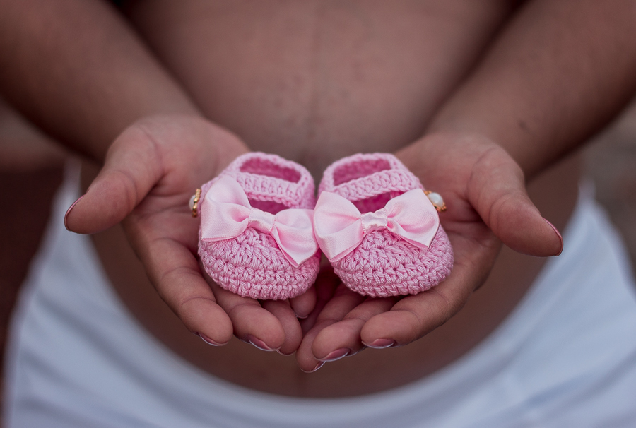 ENSAIO FOTOGRAFICO DE GESTANTES NO PARQUE DO JAPAO EM UMA TARDE ENSOLARADA EM MARINGA PARANA BRASIL NA IMAGEM DE DETALHE ESTA A MAE SEGURANDO UM SAPATINHO ROSA DE CROCHÊ COM MUITO CARINHO