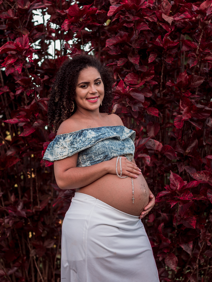 ENSAIO FOTOGRAFICO DE GESTANTES NO PARQUE DO JAPAO EM UMA TARDE ENSOLARADA EM MARINGA PARANA BRASIL NA IMAGEM A GESTANTE SEGURA UM TERCO NA BARRIGA ESTANDO EM FRENTE A UMA FOLHAGEM VERMELHO FORTE