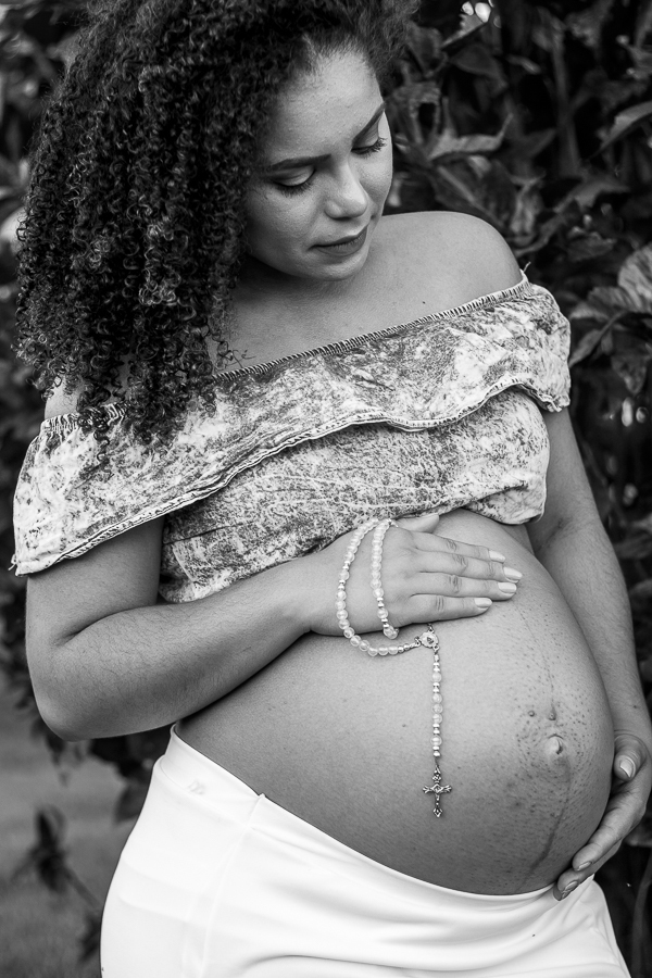 ENSAIO FOTOGRAFICO DE GESTANTES NO PARQUE DO JAPAO EM UMA TARDE ENSOLARADA EM MARINGA PARANA BRASIL NA IMAGEM EM PRETO E BRANCO A MAMAE SEGURA UM TERCO QUE SIMBOLIZA SUA FE EM SUA BARRIGA EM FRENTE A UMA FOLHAGEM VERMELHA FORTE