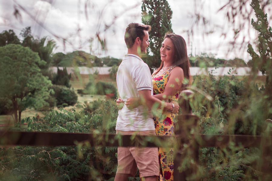 ENSAIO FOTOGRÁFICO PRÉ-WEDDING PRE WEDDING PREWEDDING DE CASAL PARQUE DO JAPAO MARINGA PARANA NA FOTO O CASAL APARECE ENTRE AS FOLHAS EM CIMA DA PONTE SE ABRACANDO DE FRENTE E TROCANDO OLHARES