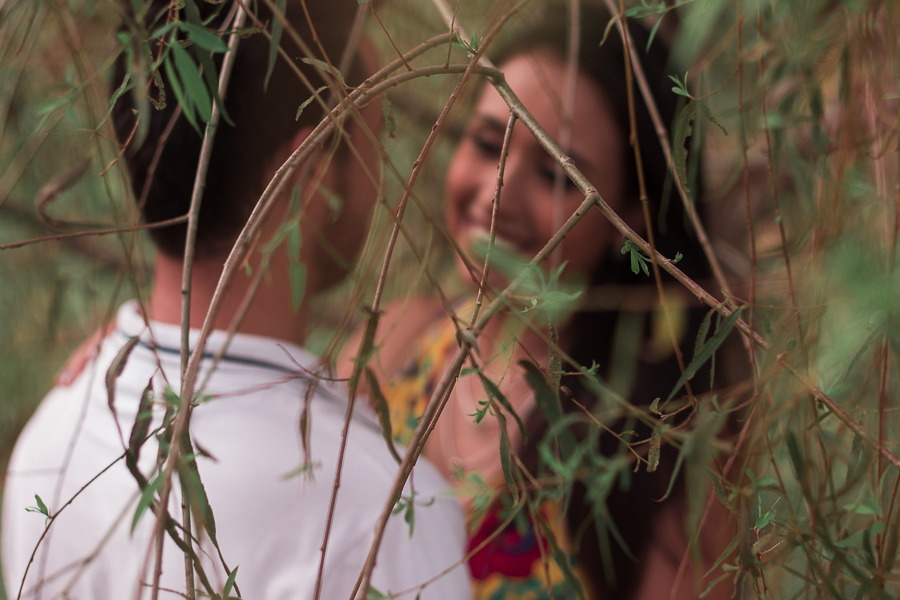 ENSAIO FOTOGRÁFICO PRÉ-WEDDING PRE WEDDING PREWEDDING DE CASAL PARQUE DO JAPAO MARINGA PARANA NA FOTO COM PRIMEIRO PLANO FOCADO APARECEM ENTRE AS FOLHAS E GALHOS O CASAL SE OLHANDO E NAMORANDO