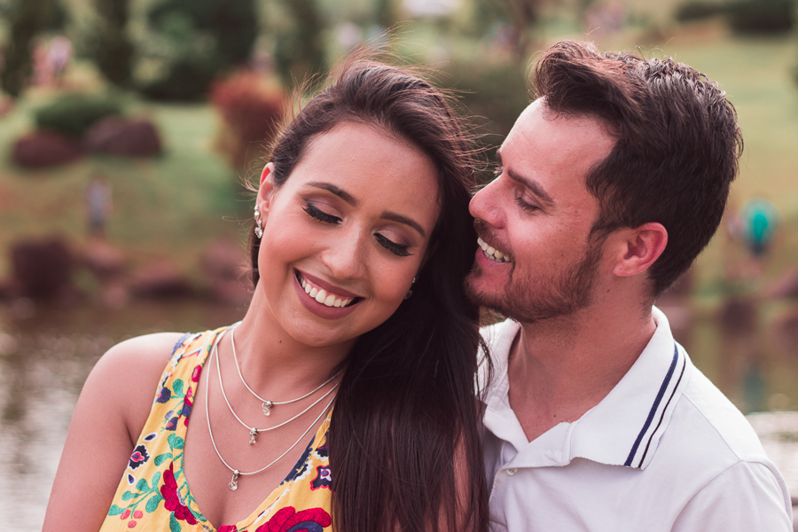 ENSAIO FOTOGRÁFICO PRÉ-WEDDING PRE WEDDING PREWEDDING DE CASAL PARQUE DO JAPAO MARINGA PARANA NA FOTO OS NOIVOS ESTAO SORRINDO APOS O NOIVO TER BEIJADO A CABECA DA NOIVA DE  FUNDO UMA LAGOA DESFOCADA
