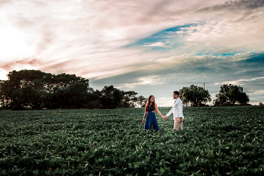 ENSAIO PRE WEDDING MANDAGUACU PARANA PRE CASAMENTO MARINGA FOTO FEITA DE LONGE QUANDO O CASAL ESTAVA ANDANDO PELO CAMPO ENQUANTO SE OLHAVAM LUZ NATURA COM O CEU AZUL 