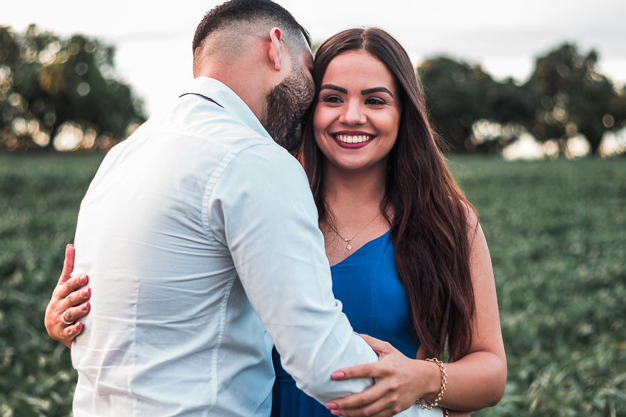 ENSAIO PRE WEDDING MANDAGUACU PARANA PRE CASAMENTO MARINGA O CASAL ESTA ABRAÇADO ELA ESTA DE FRENTE OLHANDO PARA A CAMERA  E ELE DE COSTAS COM O ROSTO PROXIMO AO DELA