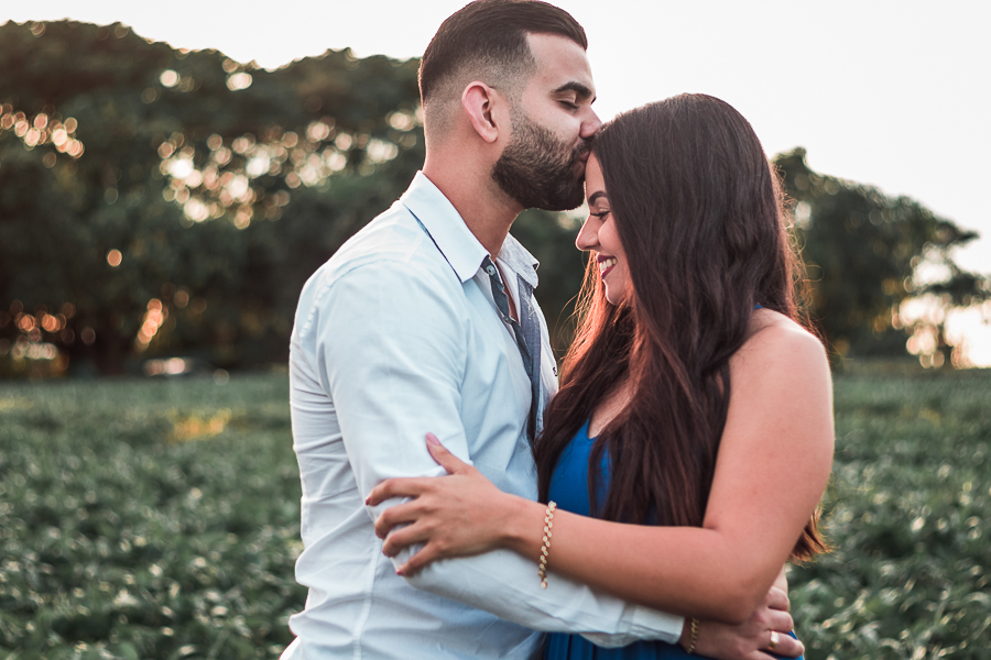 ENSAIO PRE WEDDING MANDAGUACU PARANA PRE CASAMENTO MARINGA O CASAL ESTA ABRAÇADO EM UM ESPAÇO NATURAL ELE DANDO UM BEIJO EM SUA TESTA E ELA COM OS OLHOS FECHADOS E COM UM LEVE SORRISO 