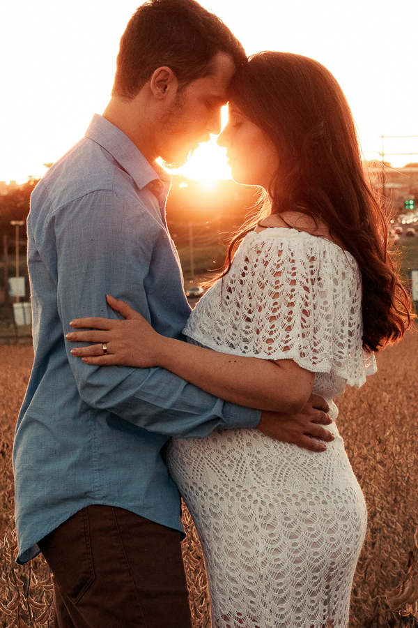 ENSAIO FOTOGRAFICO DE GESTANTE GESTACAO REALIZADO EM MARINGA NO PARANA NA IMAGEM A MAMAE APARECE COM UM VESTIDO BRANCO NA IMAGEM O CASAL APARECE ABRACADOS COM A LUZ DO SOL VINDO DE CONTRA
