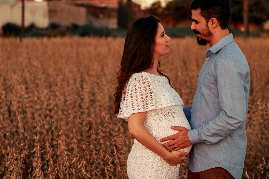 ENSAIO FOTOGRAFICO DE GESTANTE GESTACAO REALIZADO EM MARINGA NO PARANA NA IMAGEM A MAMAE APARECE COM UM VESTIDO BRANCO NA IMAGEM O CASAL ESTA ABRACADO ENQUANTO O PAI PROFERE ALGUMAS PALAVRAS PARA A MAE