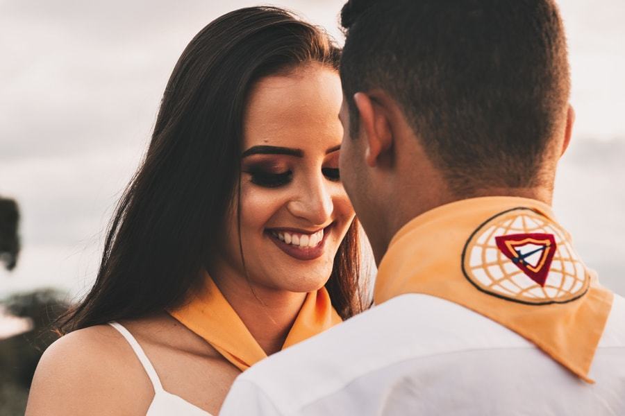 CASAMENTO OU PRE WEDDING REALIZADO EM MARINGA PARANA COM UM CASAL JOVEM A CEU ABERTO NA IMAGEM A NOIVA ESTA AJUSTANDO O LENCO DOS DESBRAVADORES DO NOIVO COM MUITO CARINHO
