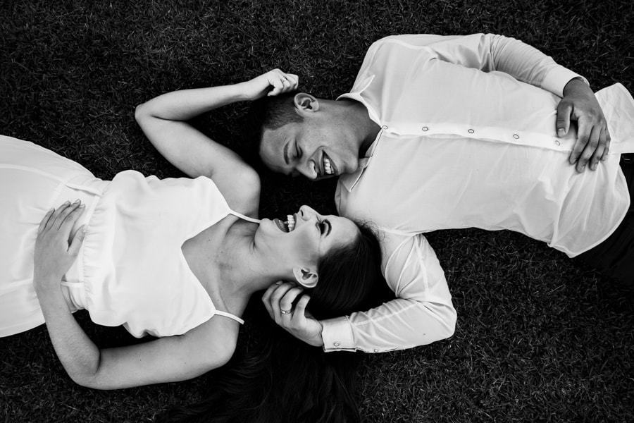 CASAMENTO OU PRE WEDDING REALIZADO EM MARINGA PARANA COM UM CASAL JOVEM A CEU ABERTO NA IMAGEM O CASAL ESTA DEITADO NA GRAMA  E SORRINDO FOTO EM PRETO E BRANCO