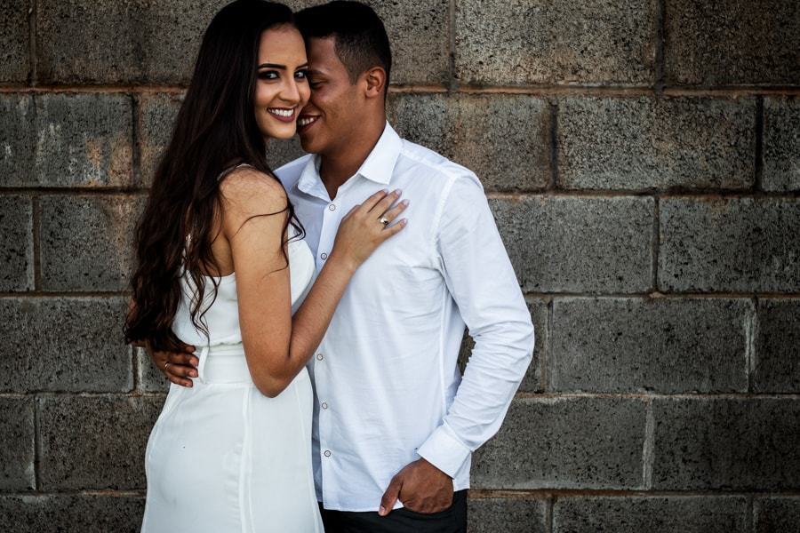 CASAMENTO OU PRE WEDDING REALIZADO EM MARINGA PARANA COM UM CASAL JOVEM A CEU ABERTO NA IMAGEM O CASAL ESTA EM FRENTE AO MURO ABRACADOS COM A NOIVA OLHANDO PARA A CAMERA